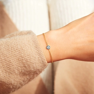 Elegant s925 sterling silver gold evil eye bracelet worn over a cozy beige knit sweater