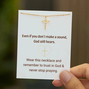 Close-up of gold cross necklace with zircon stones on a religious message card