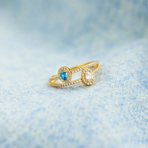 Macro shot of double-layer gold ring with blue and white oval stones and zircon pavé