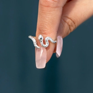 Macro detail of silver snake ring with textured scales worn on a model's finger