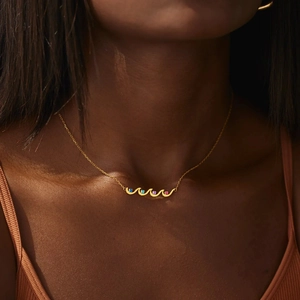 Elegant gold wave necklace with four colorful birthstones worn by a female model