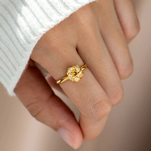 Détail d'une bague nœud en argent plaqué or sertie de zircons portée par un mannequin