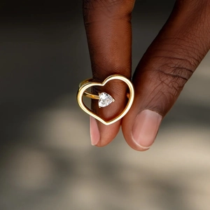 Macro detail of a gold heart ring featuring a floating zircon heart stone inlay