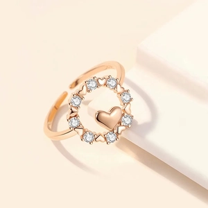 Détail d'une bague ouverte en or rose avec motifs de cœurs et zircons scintillants
