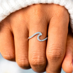 S925 sterling silver wave ring with blue zircons worn over a white knitted sweater