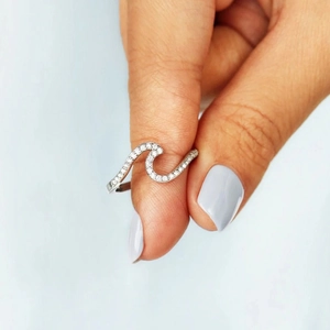 Close-up of s925 sterling silver wave ring with pavé crystals on blue background