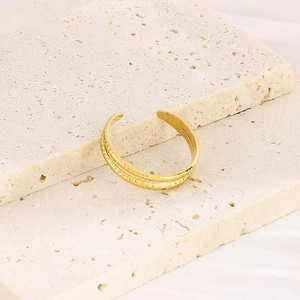 Detailansicht eines goldenen doppellagigen gedrehten Rings auf minimalistischem Stein