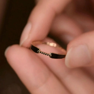 Close-up of rose gold ring with black enamel and embedded black stones on fingers