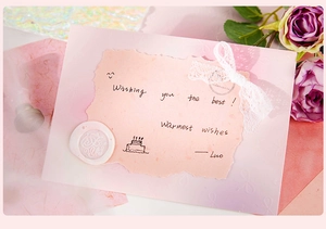 Close-up of artsy scrapbooking paper with a pink wax seal and lace bow decor