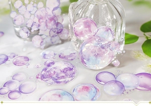 Vue détaillée de stickers bulles irisés sur bouteille en verre avec aquarelle bleue et mauve