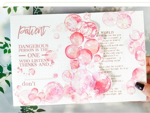 Détail de stickers PET bulles dégradé rose sur un carnet à carreaux pour scrapbooking