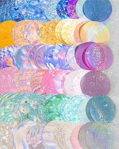 Macro shot of circular holographic glitter stickers with butterfly and floral patterns