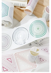 Detailed view of geometric washi tape rolls with hexagons and circles on a linen desk