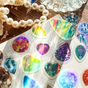 Vibrant laser-cut gemstone PET stickers with holographic effects on dark wood background