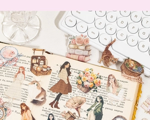Makroaufnahme von PET-Aufklebern mit Vintage-Mädchen und Katzen auf einem Journal