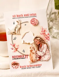 Close-up of decorative scrapbooking cards with cat and floral illustrations by a coffee cup
