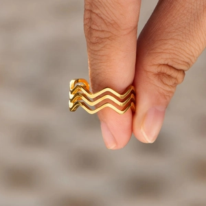 Gros plan d'une bague vague dorée à trois couches au design courbé minimaliste pour femme