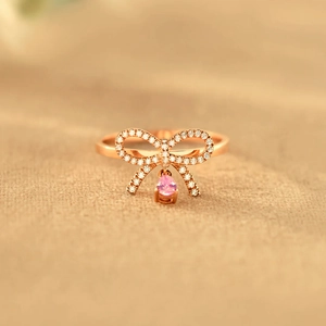 Elegant rose gold bow ring with sparkling pavé stones and pink pear-cut pendant
