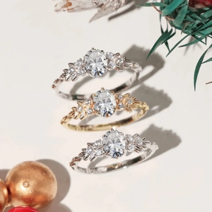Elegant leaf branch rings in silver and gold with oval zircon center stones in a festive setup