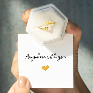 Detail of adjustable gold ring with letter V and heart on a white velvet jewelry box