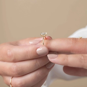 Detailed view of rectangle cut zircon ring with four-prong gold setting on finger