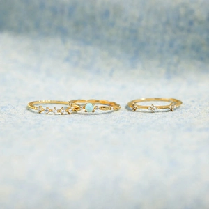 Detailed view of three gold-plated stackable rings featuring a round opal and star-set pavé