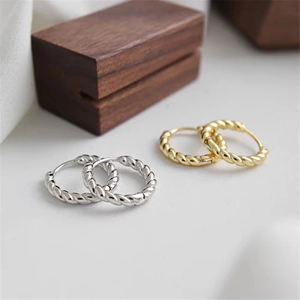 Pair of gold and silver S925 sterling silver twisted rope hoop earrings on display