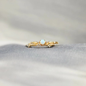 Close-up of gold-plated stacking rings set featuring opal stone and cross-shaped diamonds