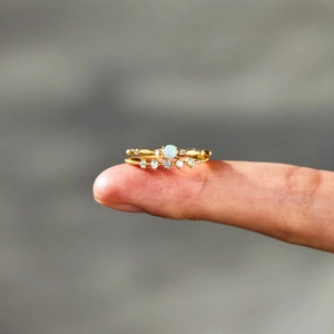 Close-up of elegant gold stacked rings with opal gemstone and pavé diamond detailing
