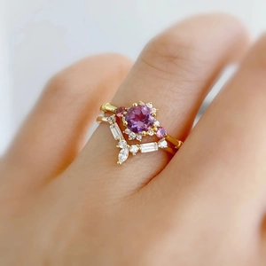 Macro shot of gold crown ring featuring a round purple gemstone and mixed crystal clusters