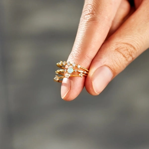 Detailed close-up of three gold stacking rings with opal and sparkling crystal pavé