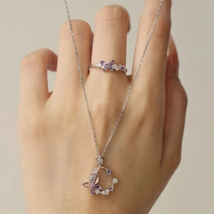 Parure bague et collier en argent S925 avec pierres papillon violettes portés par un mannequin