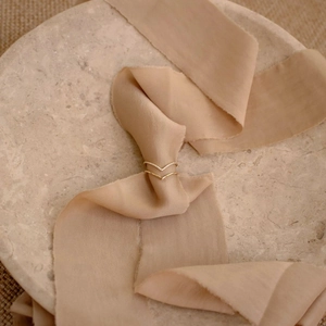 Detail of gold chevron rings set with pavé cubic zirconia on soft pink silk ribbon