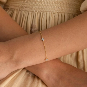 Détail d'un bracelet doré à trèfles avec incrustations de pierres blanches au poignet