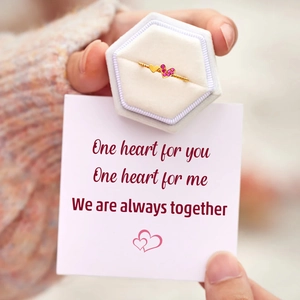 Close-up of dual heart ring with pink zircon and twisted band in a velvet gift box