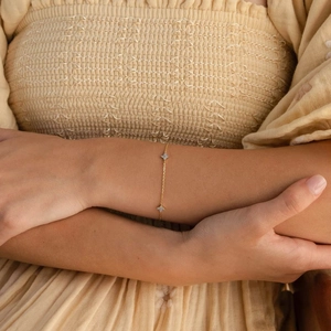Détail d'un bracelet trèfle doré avec incrustation d'opale blanche porté au poignet