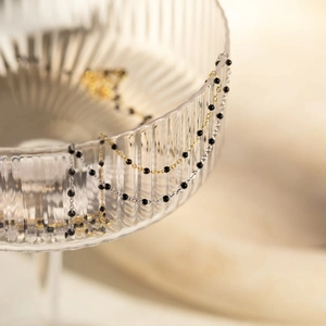 Detail of s925 silver gold chain necklace with black enamel beads on glass edge
