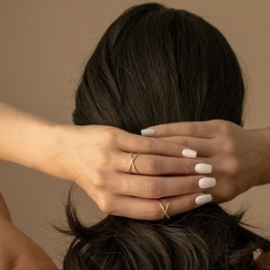 Detail of s925 silver double-layer criss cross gold rings with pavé diamonds on finger
