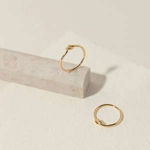 Minimalist S925 sterling silver knot rings in gold finish on marble display