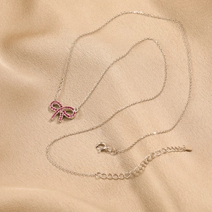 Elegant s925 silver necklace with red zircon bow pendant on champagne silk background