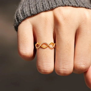Elegante anello a onda infinito dorato con zirconi incastonati sul dito