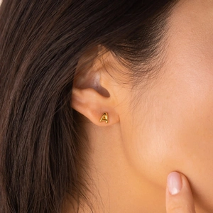 Gros plan d'une puce d'oreille en argent 925 doré en forme de lettre A au style minimaliste