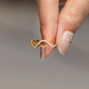 Vista macro di un anello a onda in oro 18 carati con zirconi su una fascia intrecciata