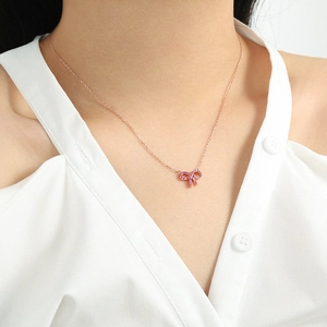 Close-up of a rose gold bow pendant necklace inlaid with sparkling pink zircon crystals