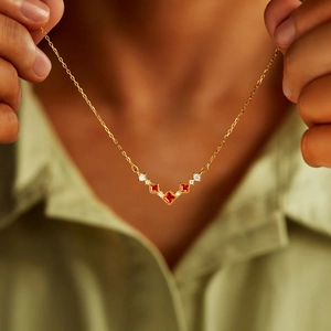 Élégant collier doré en V avec trois zircons rouges porté par un mannequin féminin