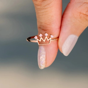 Close-up of rose gold crown ring featuring delicate pink gemstones and hollow design