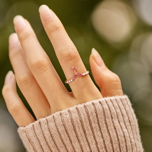 Elegant rose gold V-shaped cross ring with pink and white gemstones on a model's hand