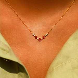 Élégant collier en V doré avec zircons rouges carrés porté par un mannequin