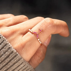 Rose gold V-shaped ring with cross design featuring pink gemstones and white pearls
