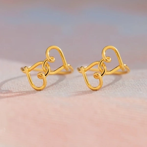S925 Silber Doppelherz Knoten Ohrringe mit Gold-Finish auf sanftem rosa Hintergrund